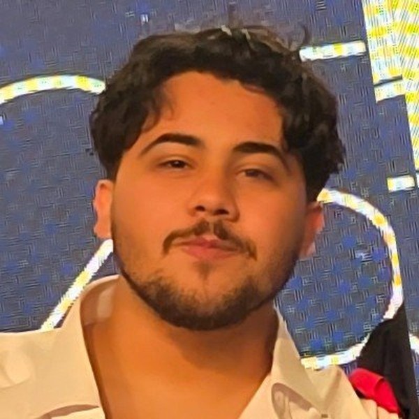 Head-and-shoulders portrait of Rami Idriss — dark curly hair, short beard, in a light collared shirt.
